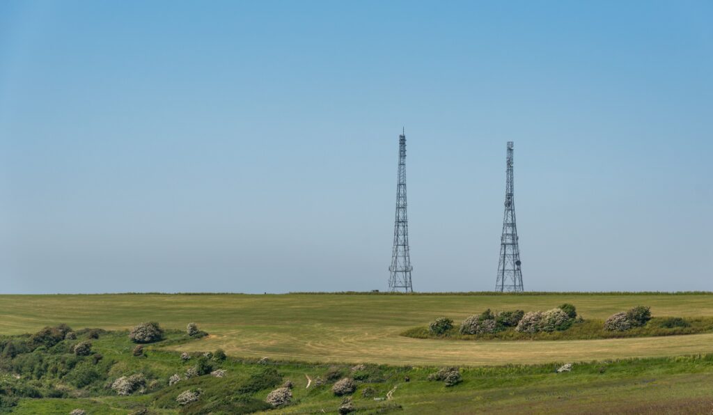 Communication tower in a green field on a cliff representing infrastructure assets monitored through Lease Management for efficient property and land use tracking.